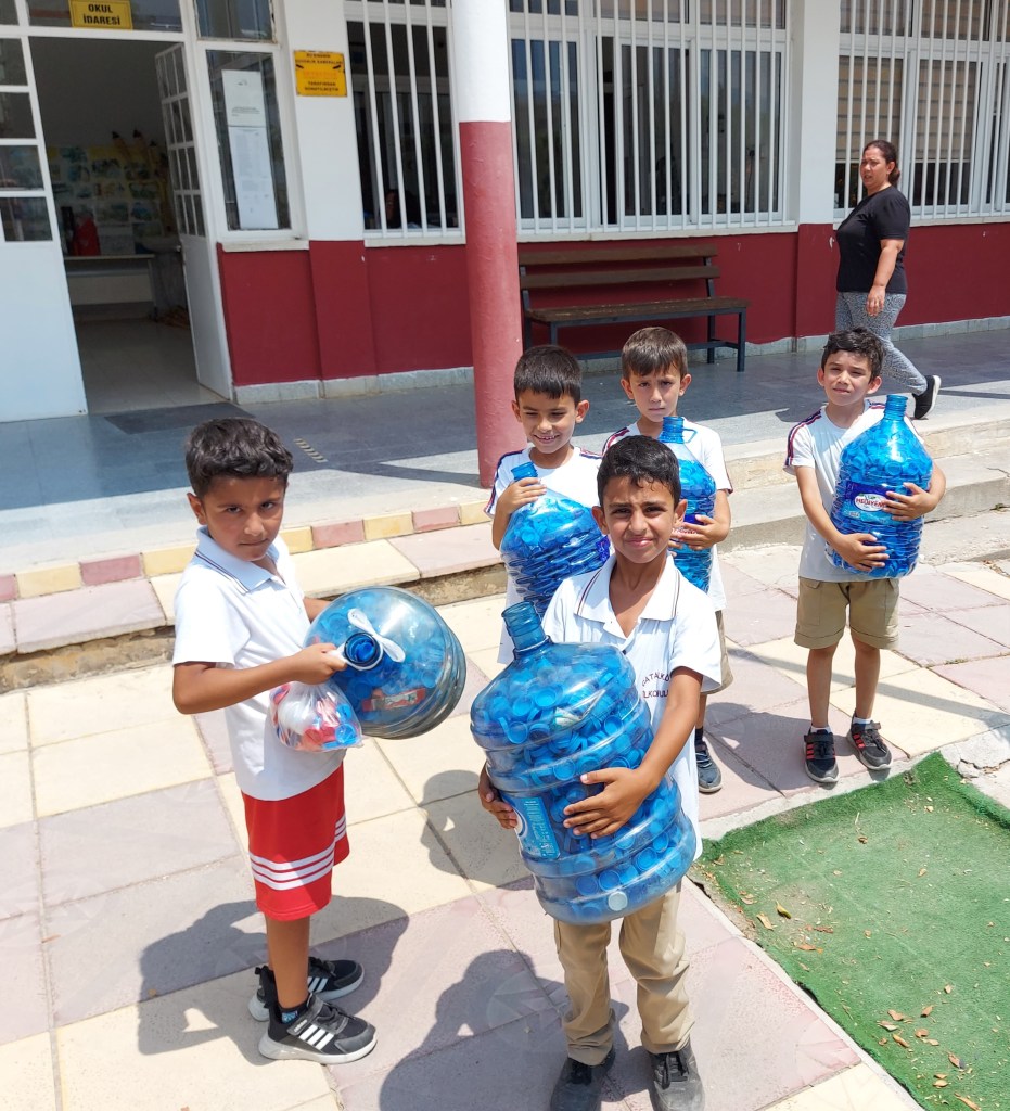 Picture showing children with collected blue bottle tops
